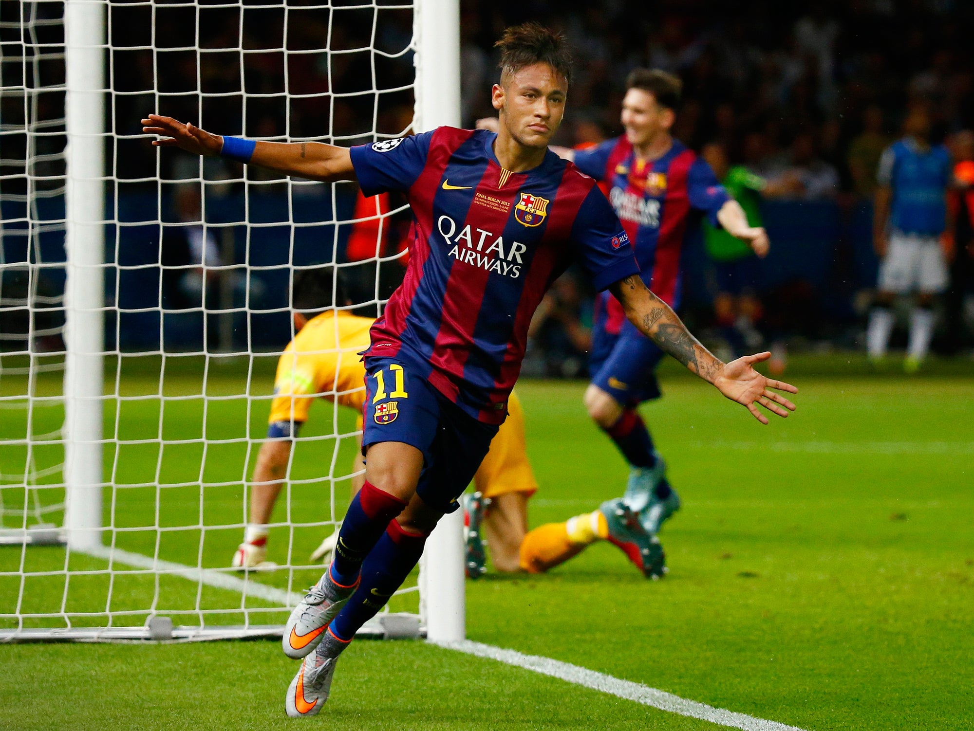 Soccer player celebrating a goal in a match, wearing a blue and red jersey with visible branding.